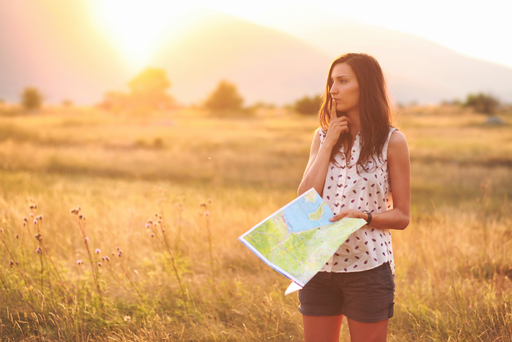 A person is looking at a map in a field at sunset