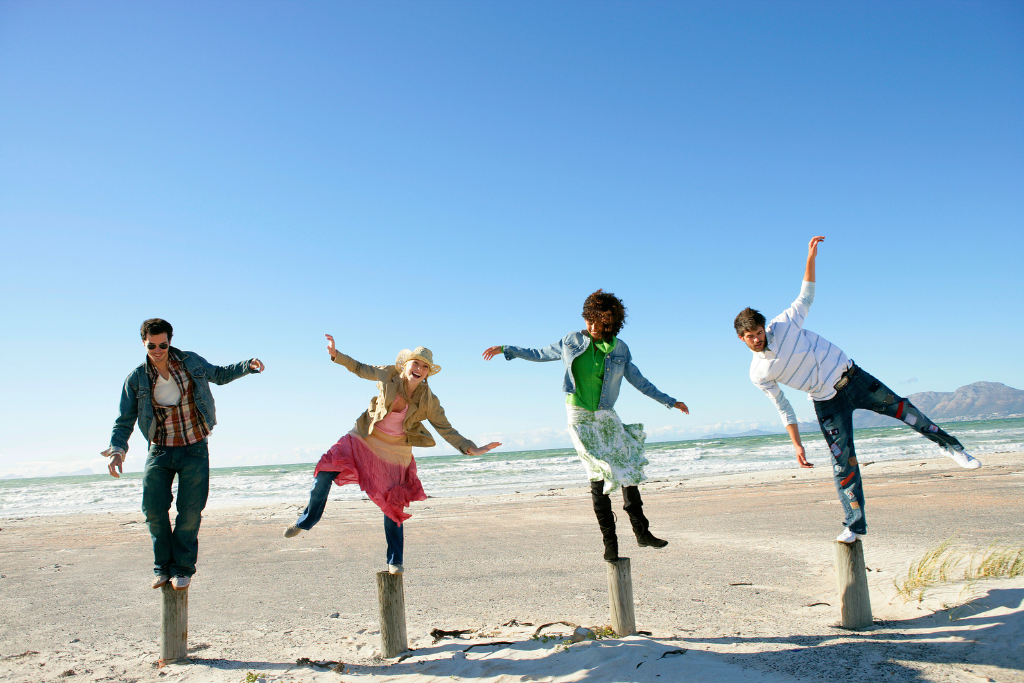People balancing on posts on a beach